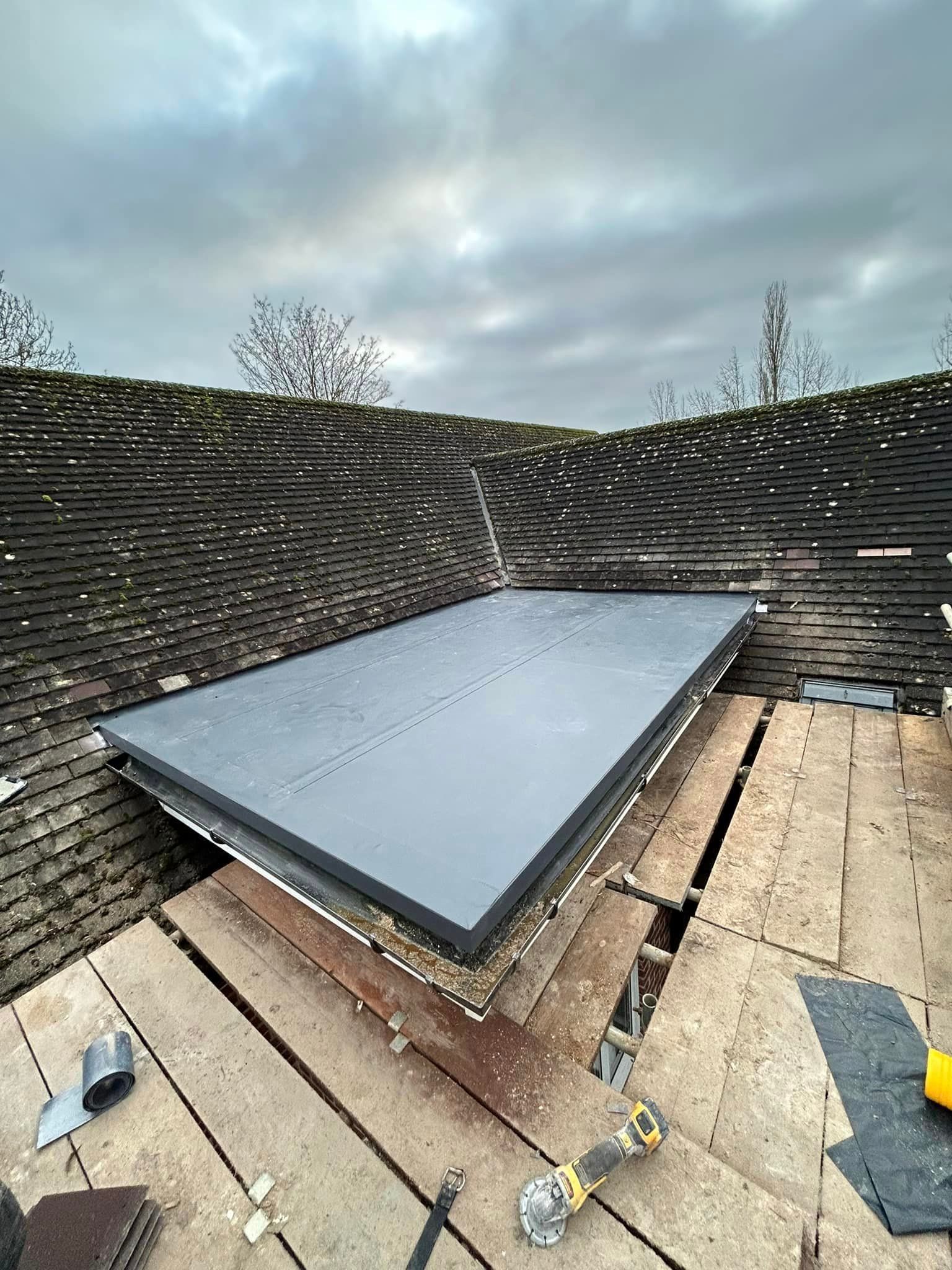 A modern flat roof is being installed next to a tiled roof
