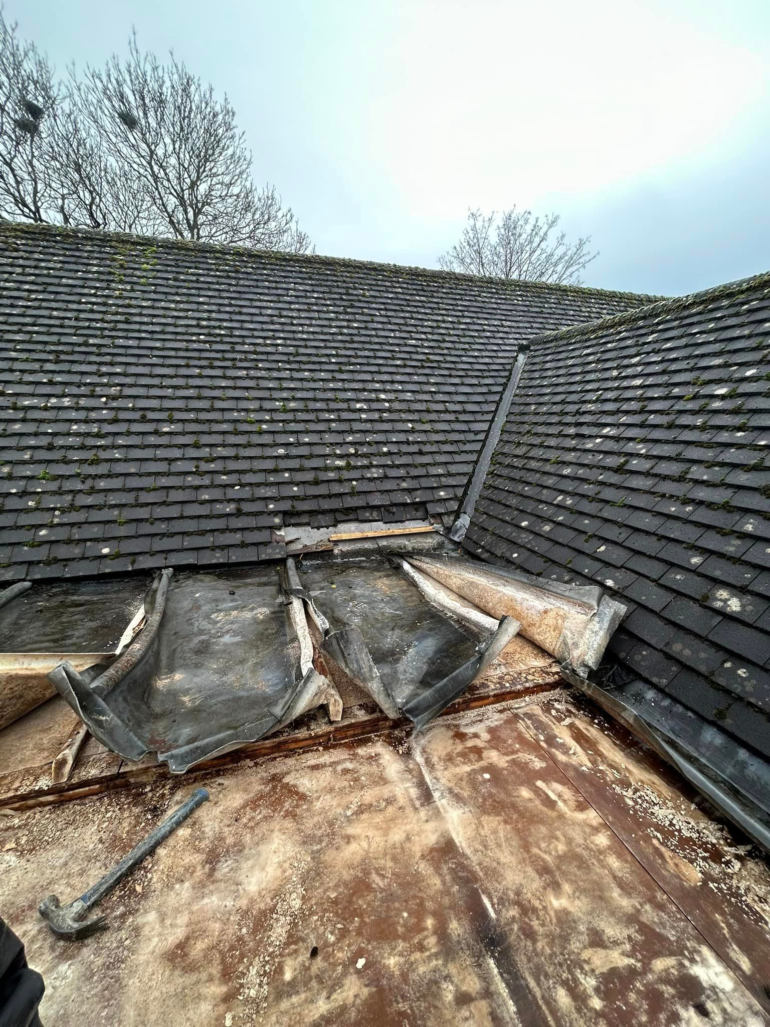 A small flat roof under repair next to a traditional slate roof.