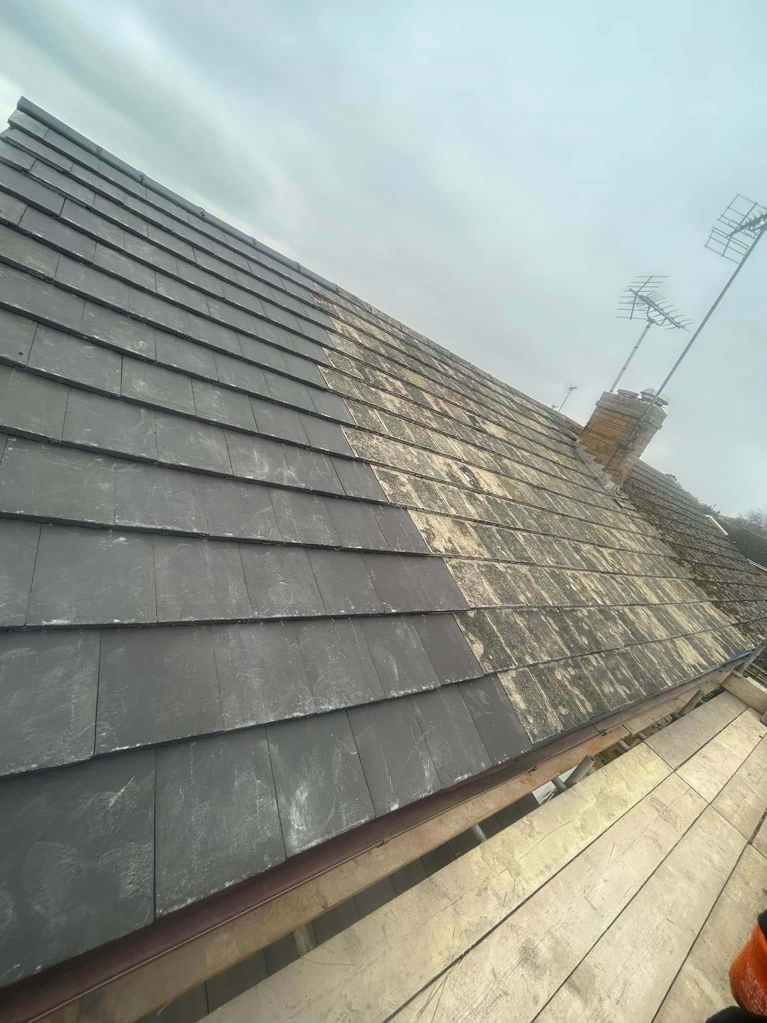 A roof with a lot of tiles on it and a chimney in the background.
