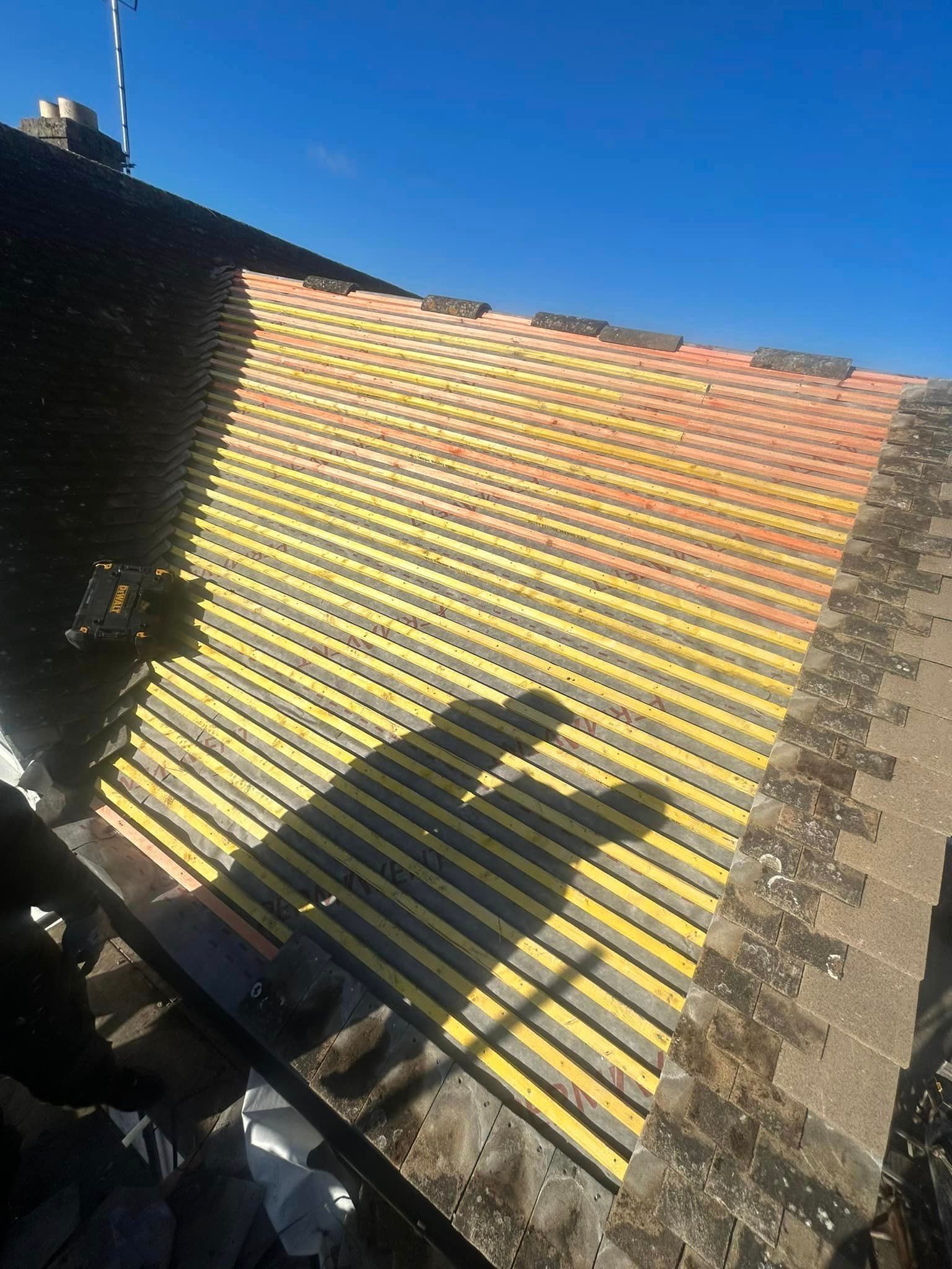 A shadow of a person is cast on the roof of a building.