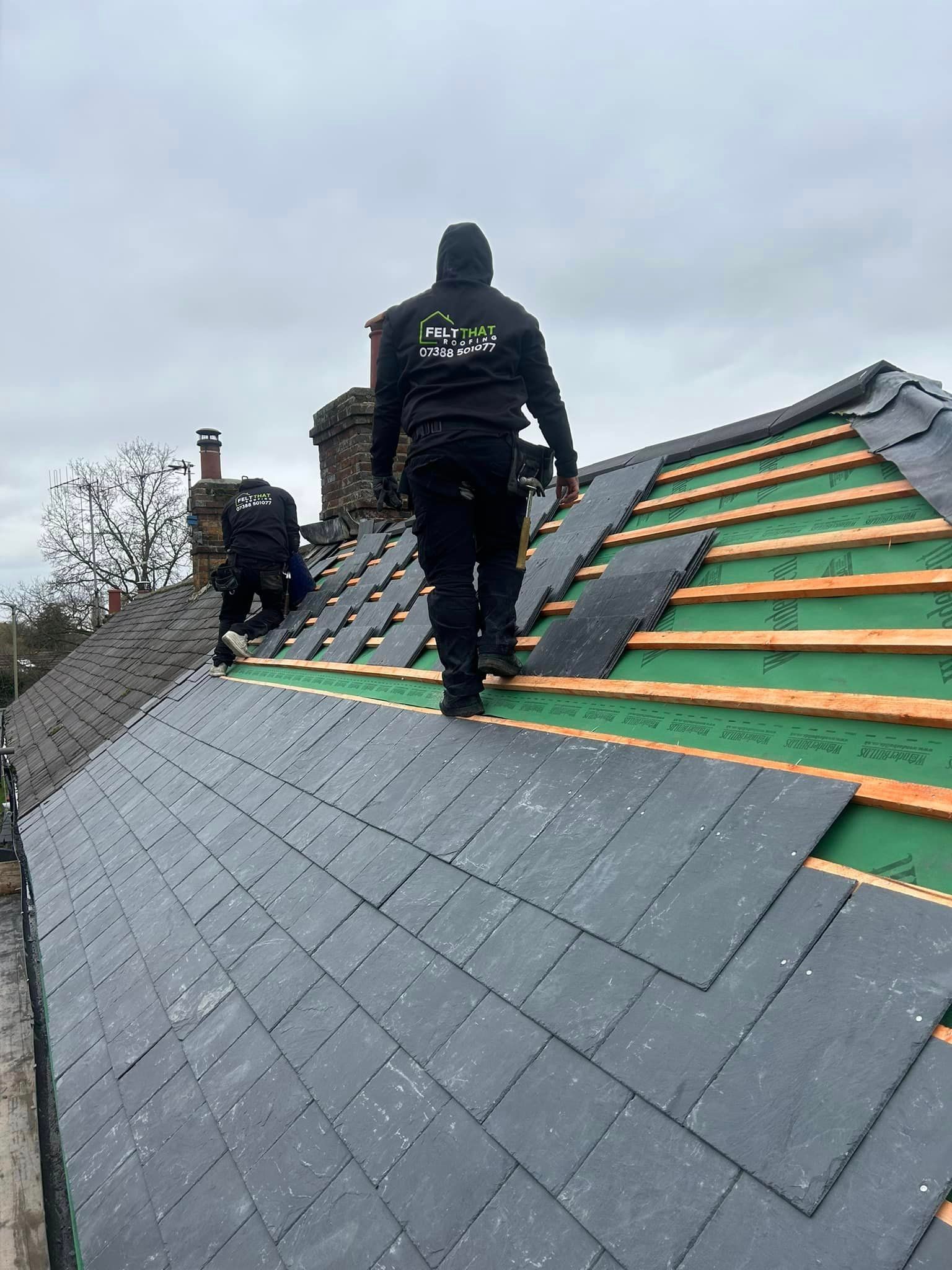 A couple of men are standing on top of a roof.