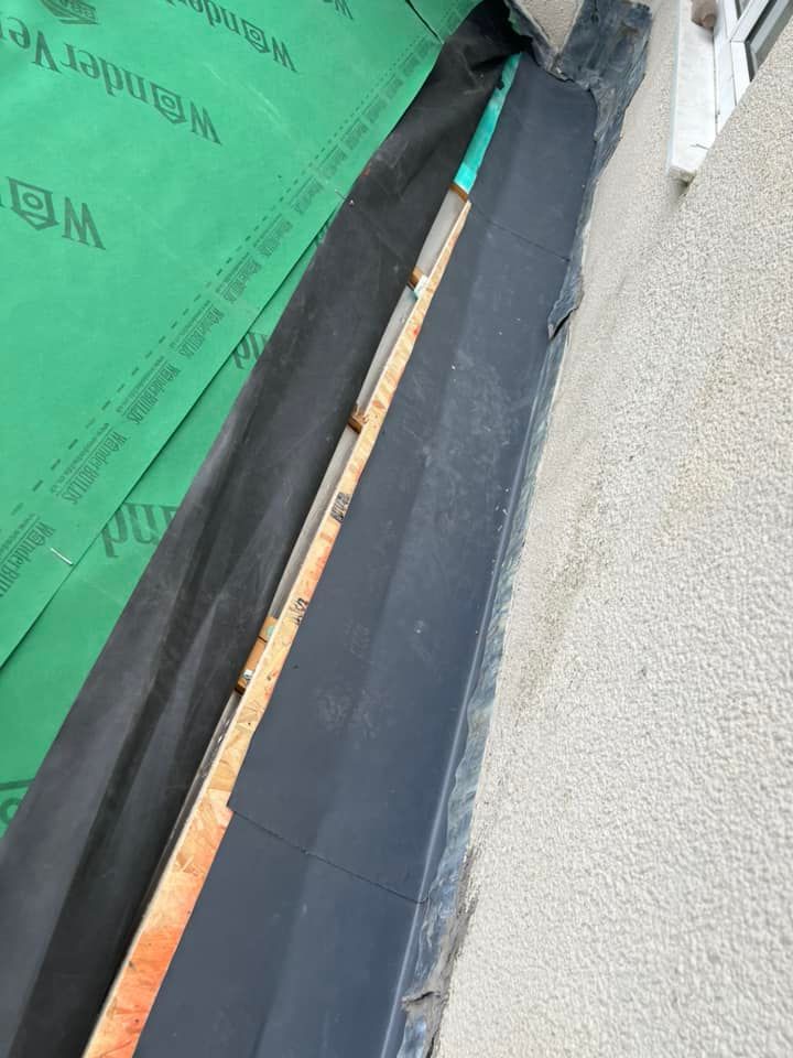 A piece of wood is sitting on top of a piece of green paper on a wall.