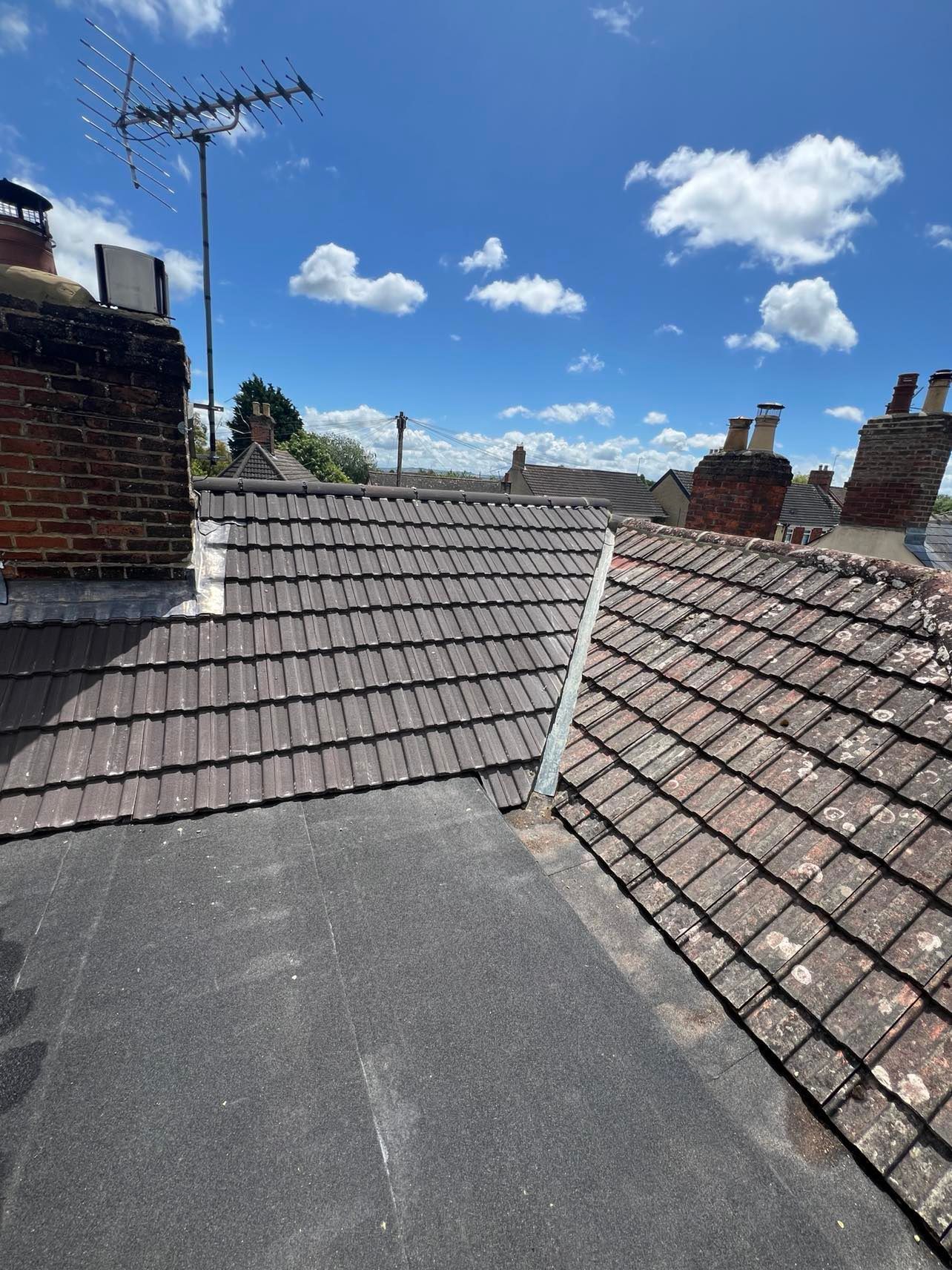 A roof with a chimney on top of it and a blue sky in the background.