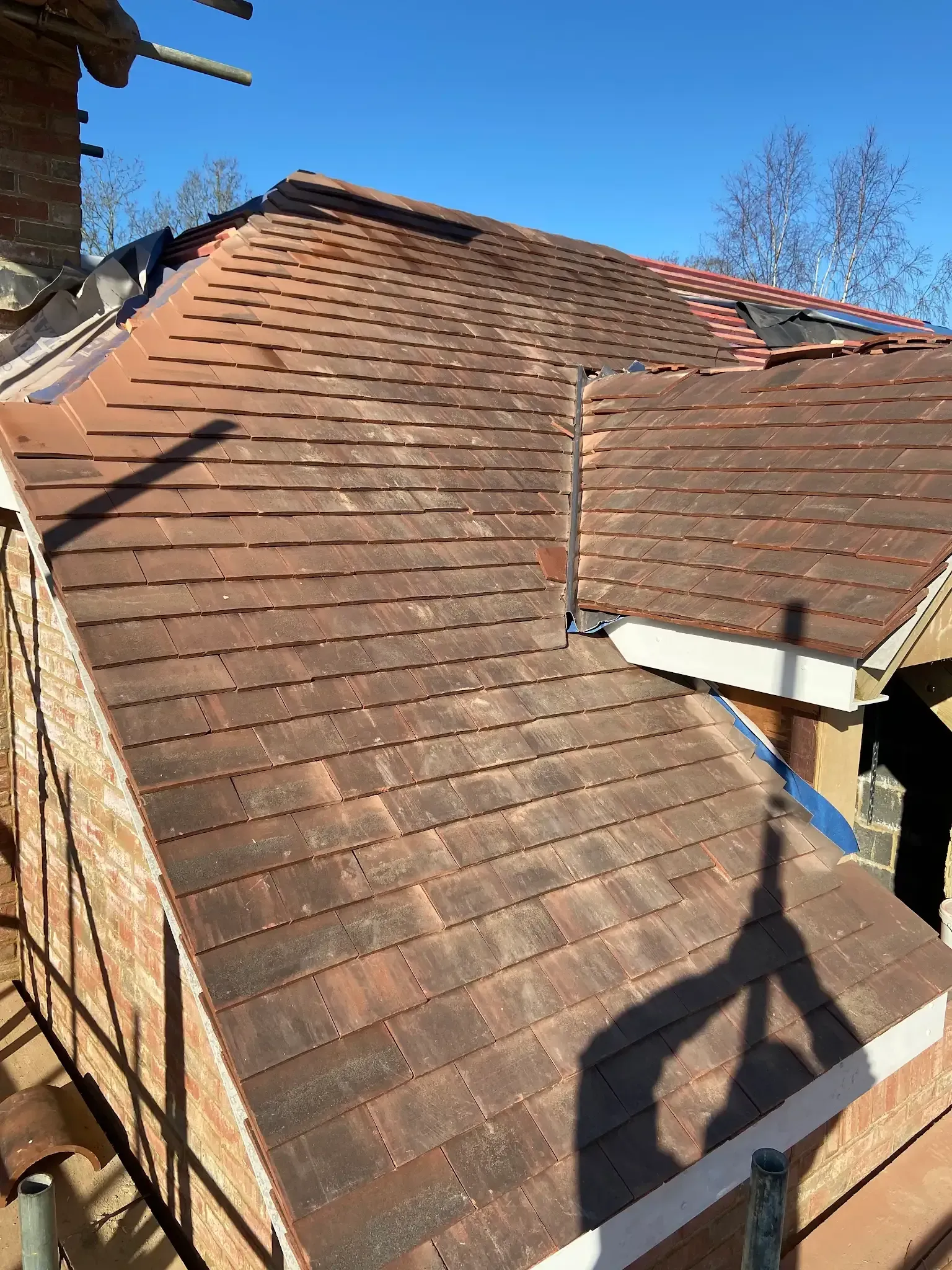 A man is standing on a scaffolding on top of a roof.