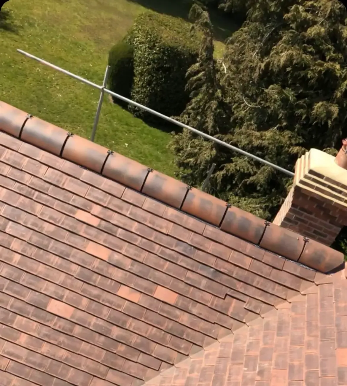An aerial view of a roof with a chimney and trees in the background