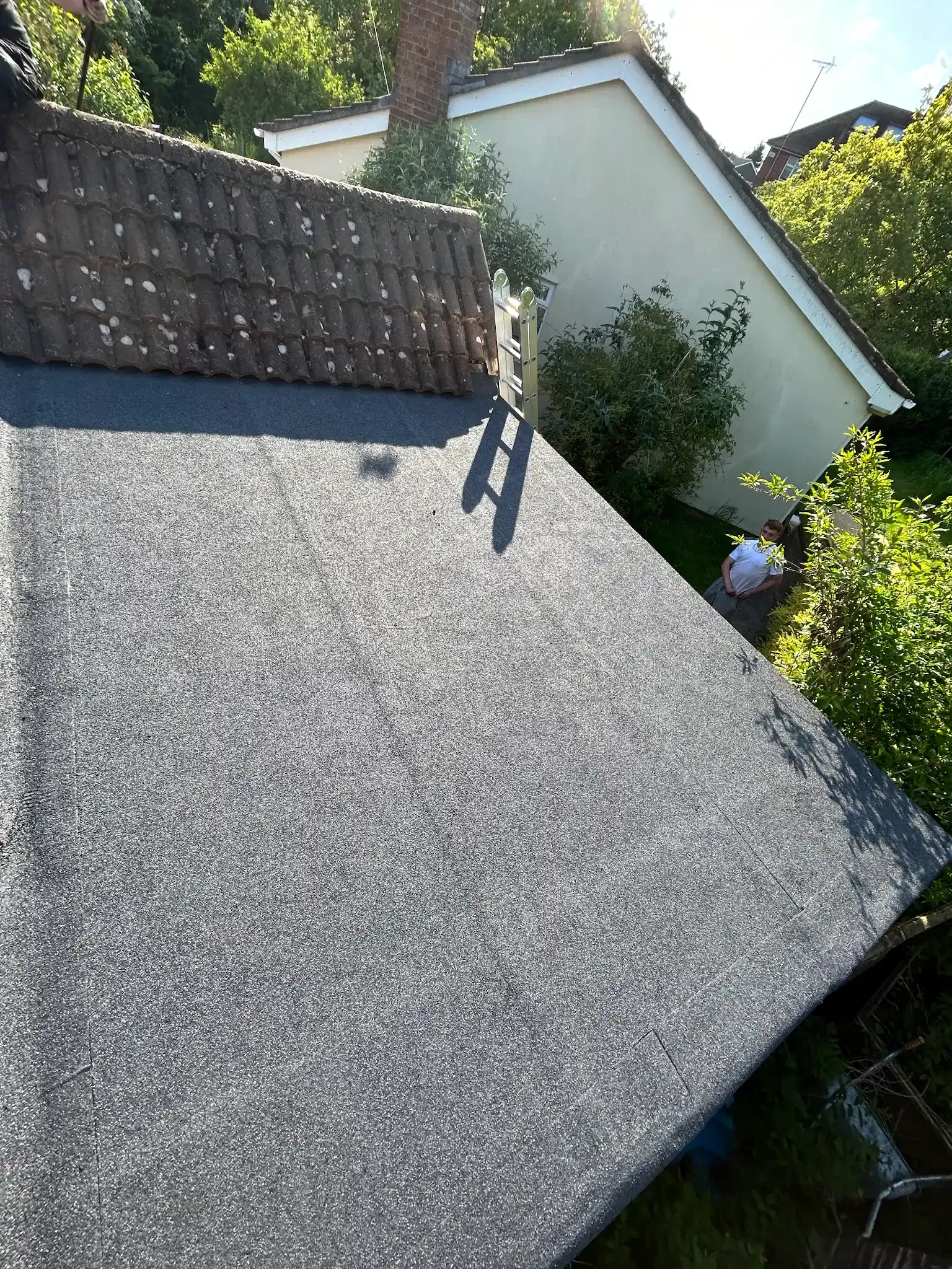 A roof with a gray roof and a white house in the background.