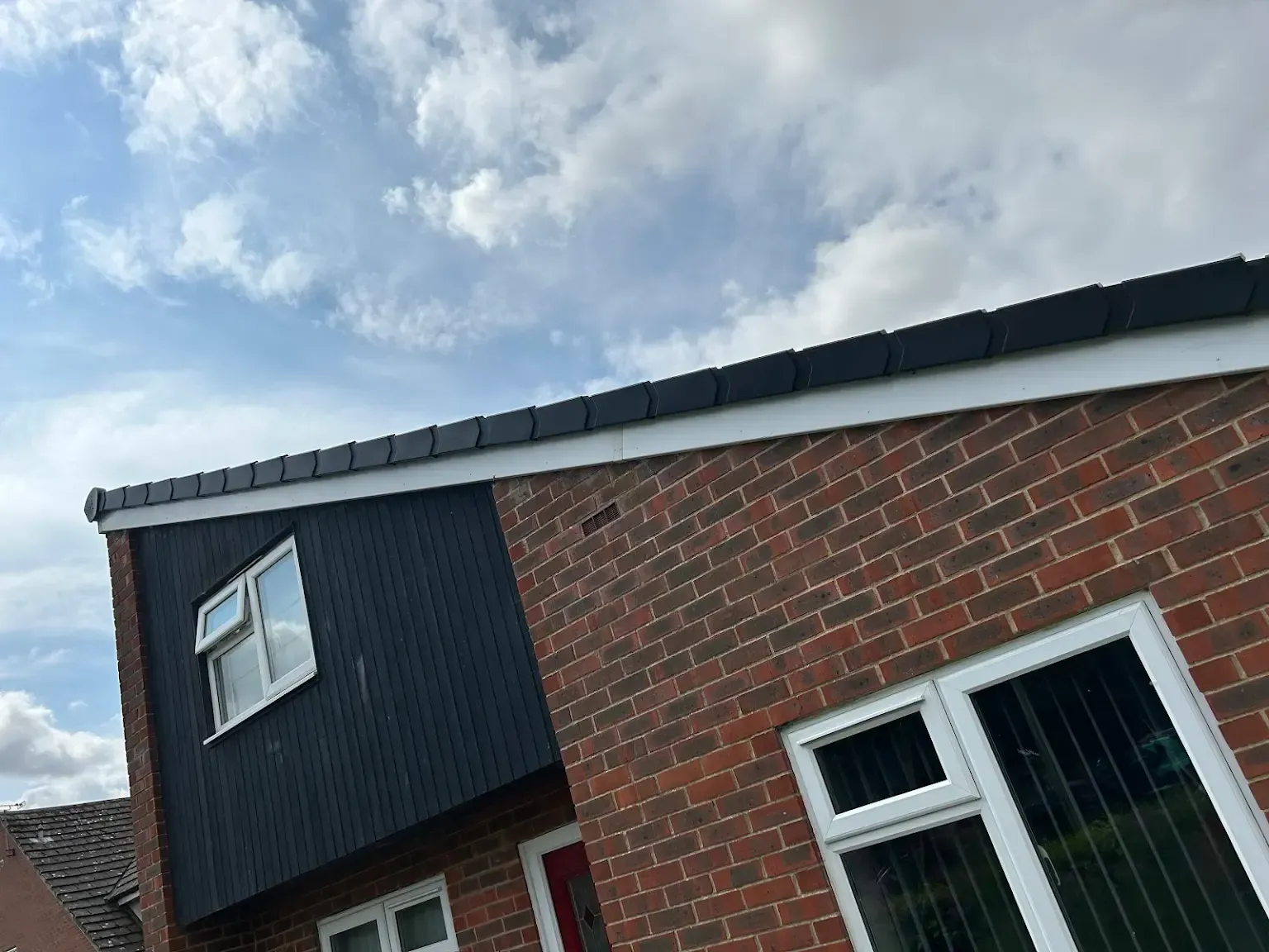 A red brick house with a black roof and white windows.
