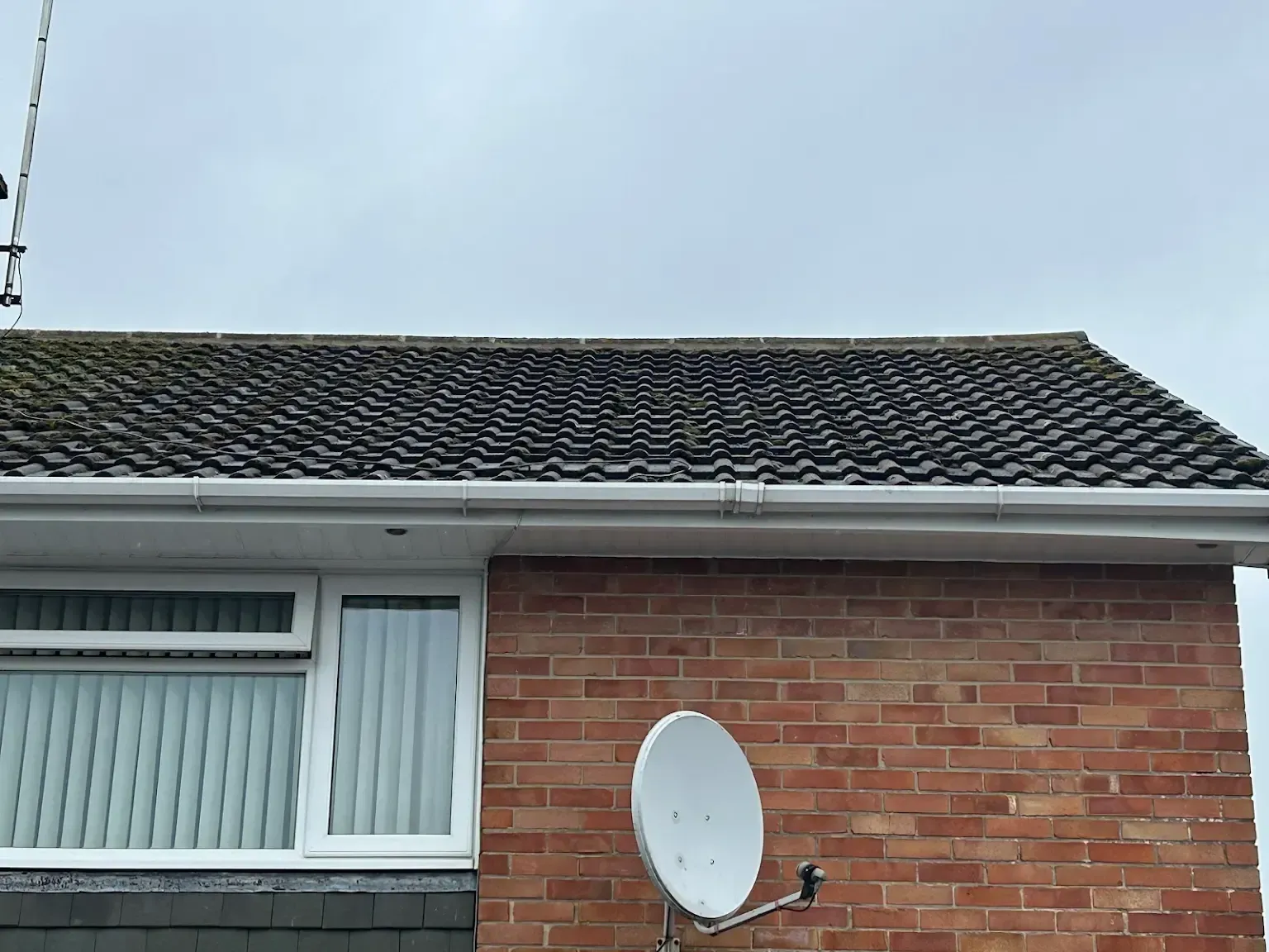 A brick house with a satellite dish on the side of it.