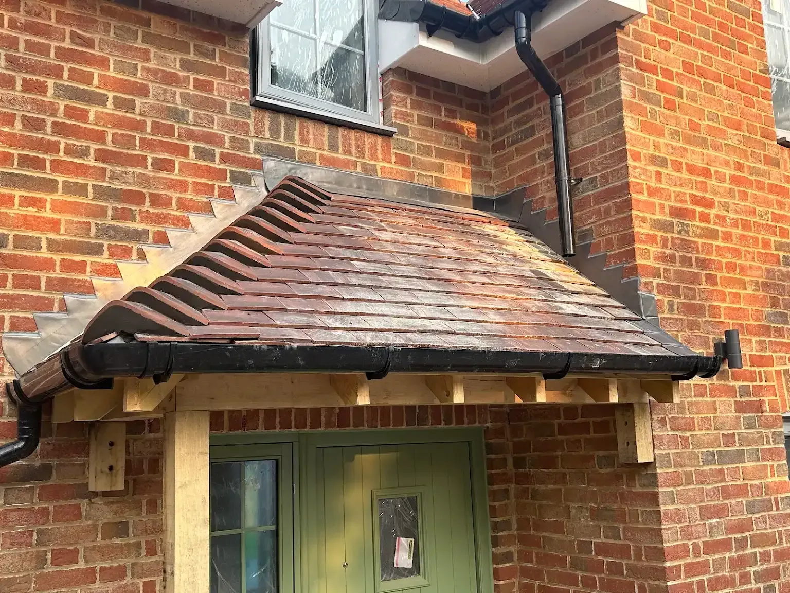 A brick house with a green door and a canopy over the door.