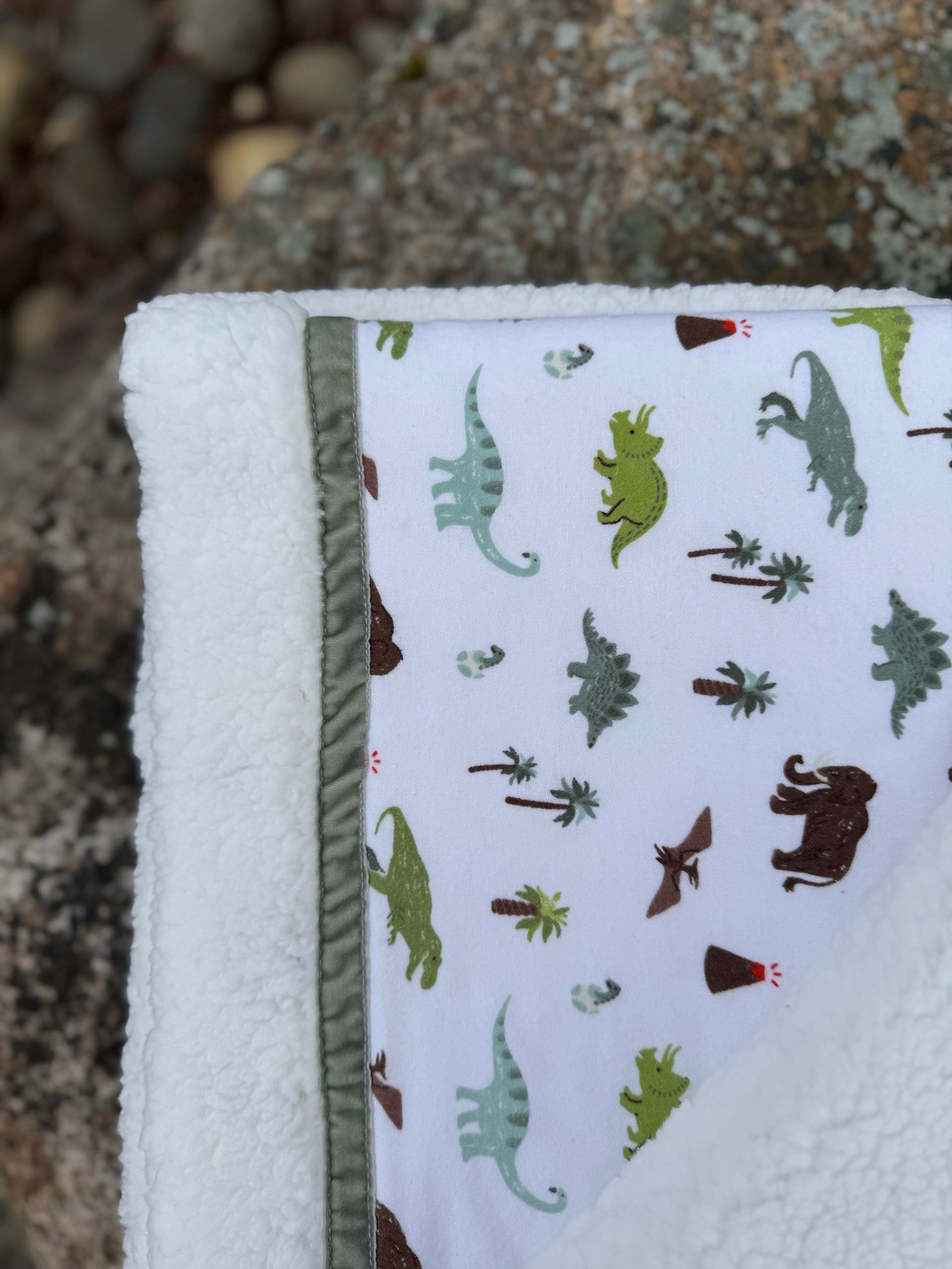 kadori sherpa baby blanket with printed dinosaur material on it