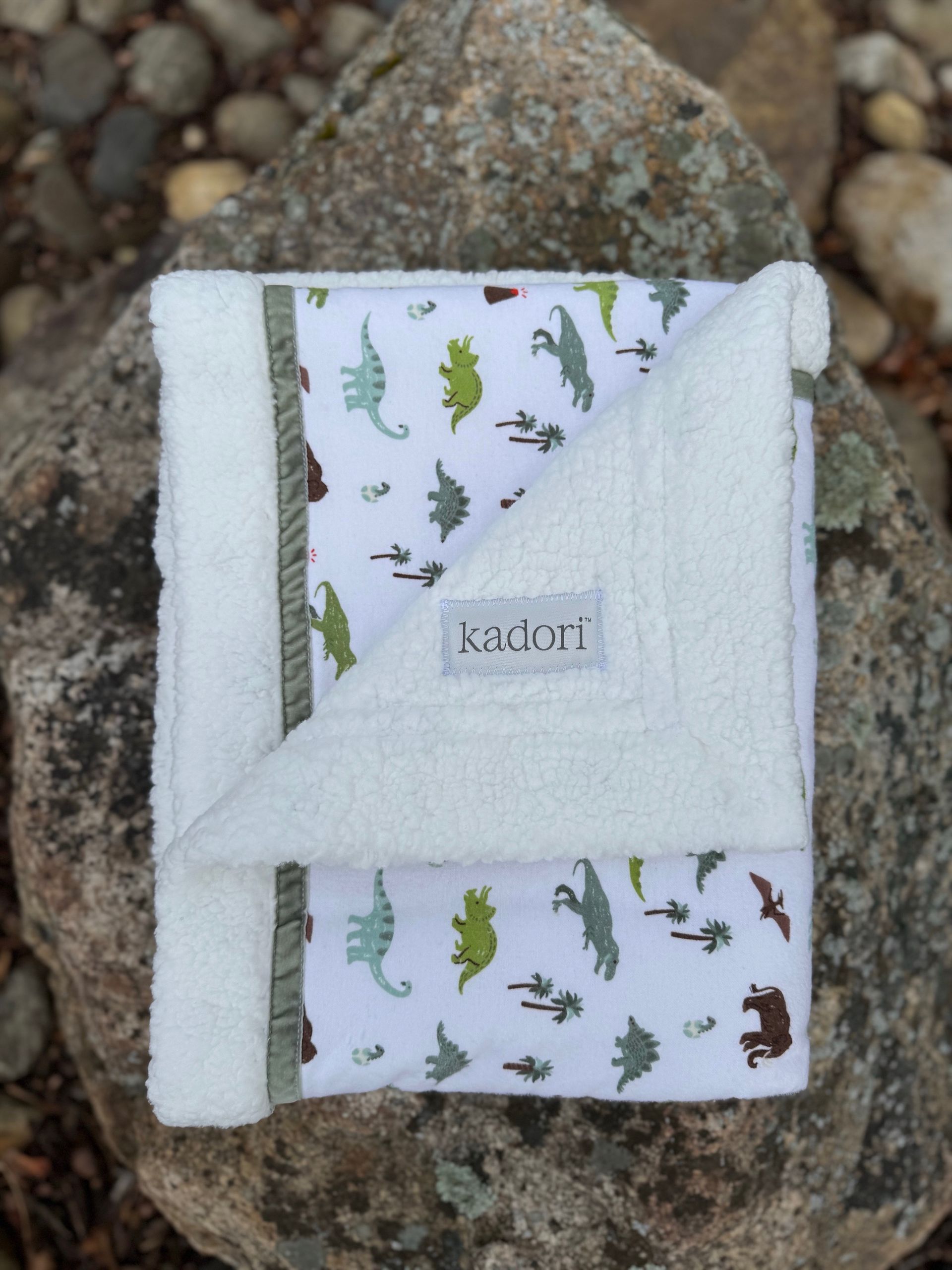 kadori sherpa baby blanket with printed dinosaur material on it