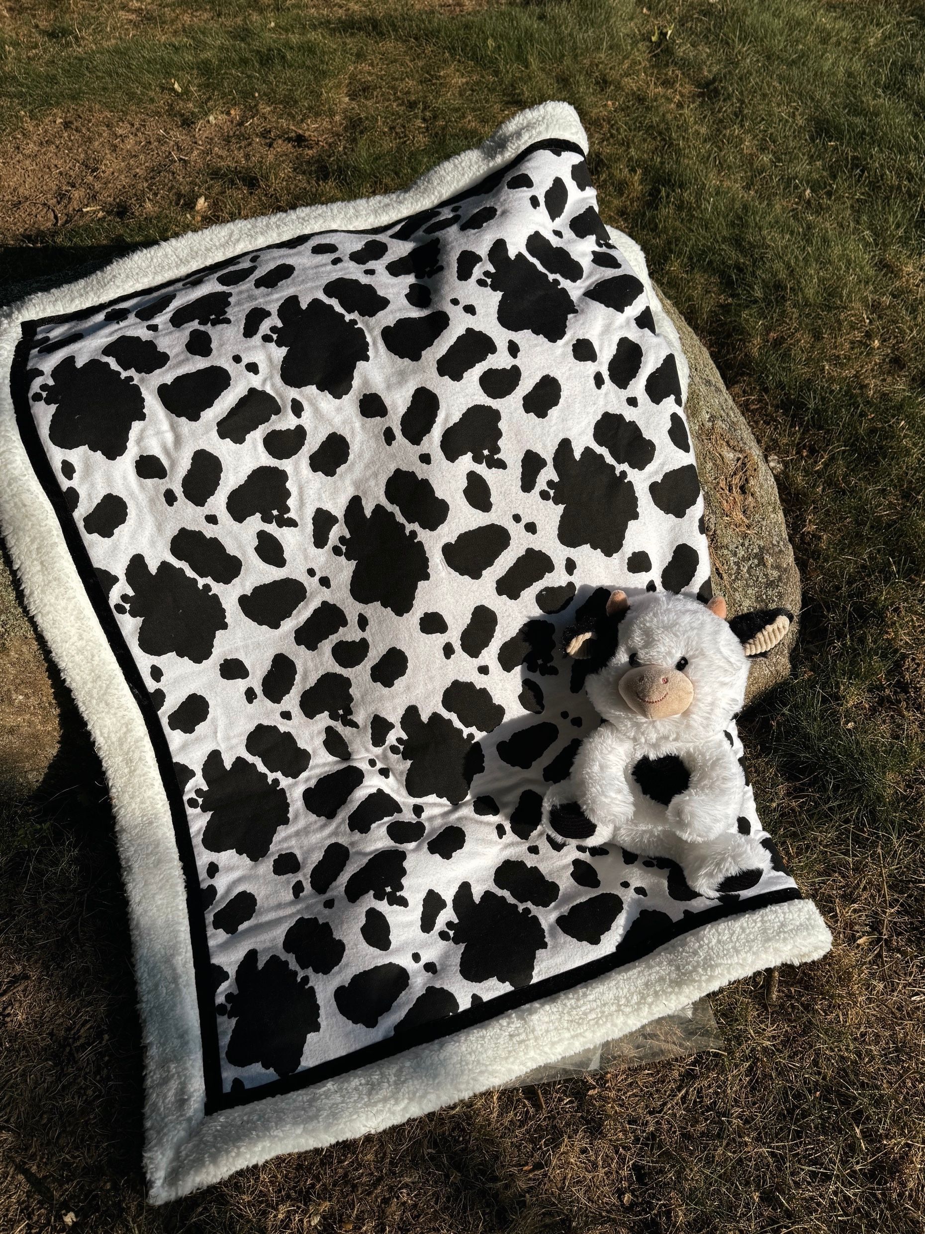 sherpa blanket with printed material that has black cow print on the fabric