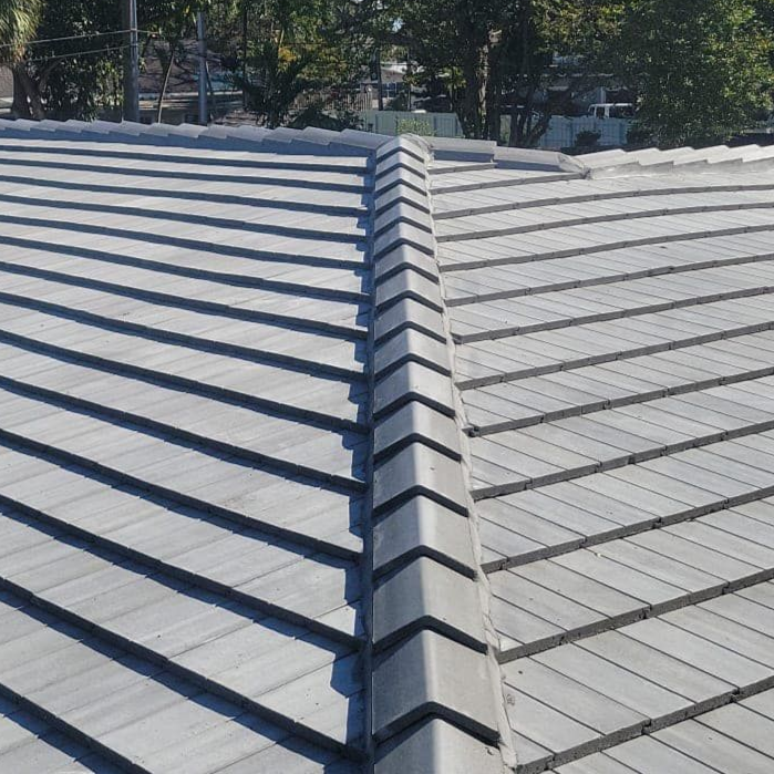 A close-up view of a gray concrete tile roof showing a prominent ridge cap running down the center.