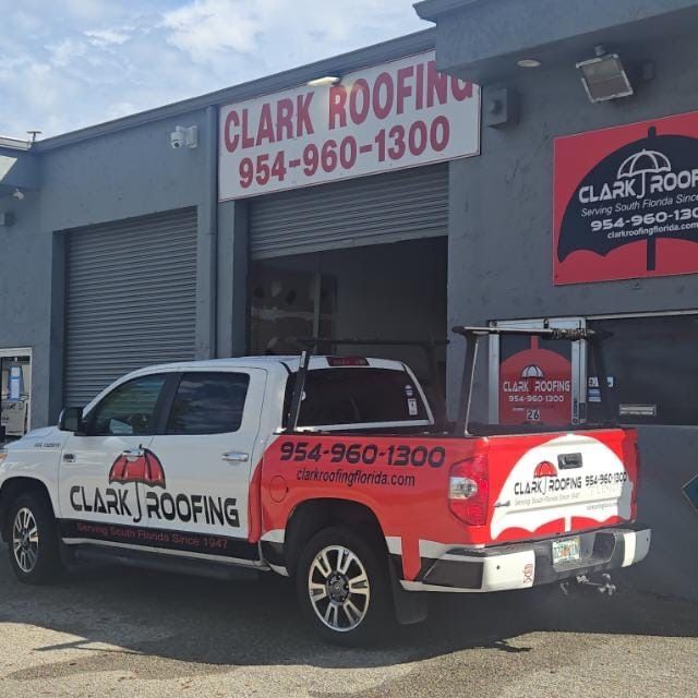 A Clark Roofing truck parked in front of a gray office building with matching company branding.