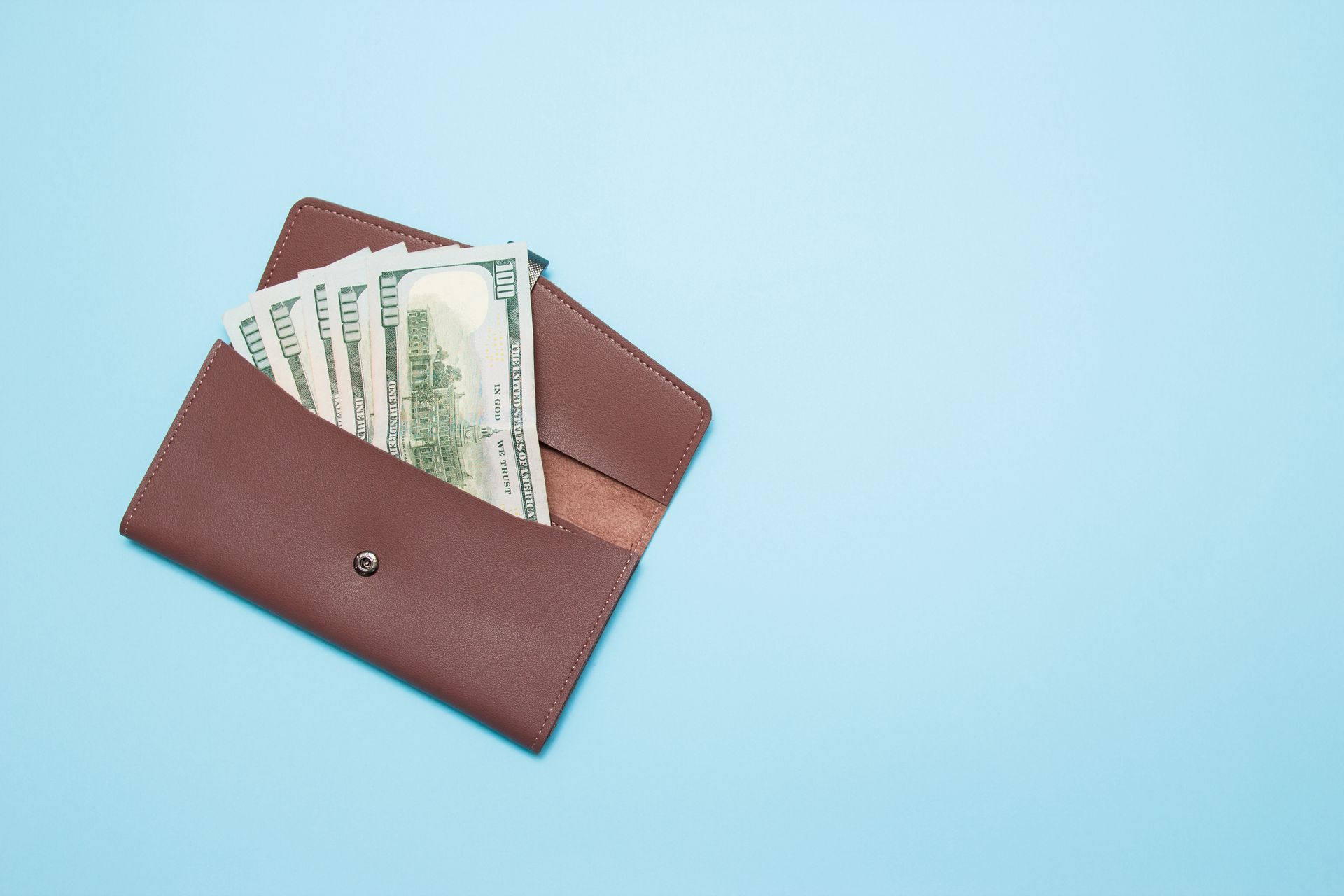 A brown wallet filled with money on a blue background.