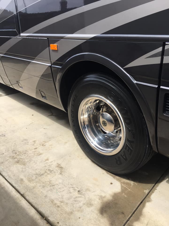 A black van with a good year tire is parked in a driveway.