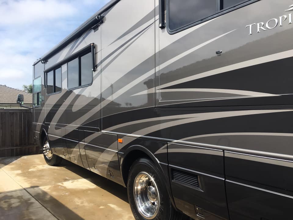 A large trophy rv is parked in a driveway