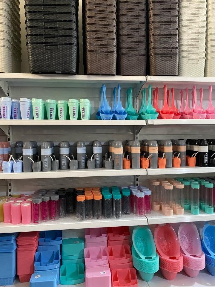 Estantes llenos de diversos recipientes de plástico de colores, vasos y macetas en una tienda.