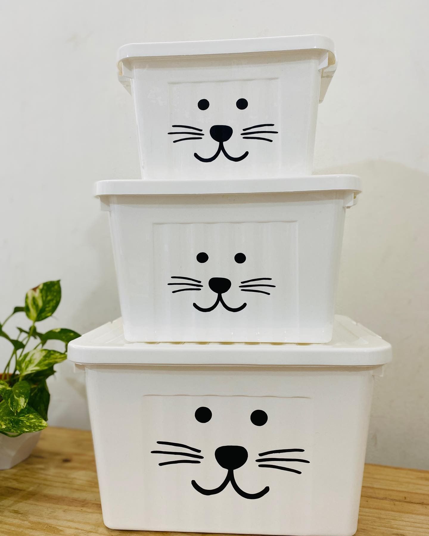 Tres contenedores de almacenamiento blancos apilados, cada uno con un diseño de cara de gato.