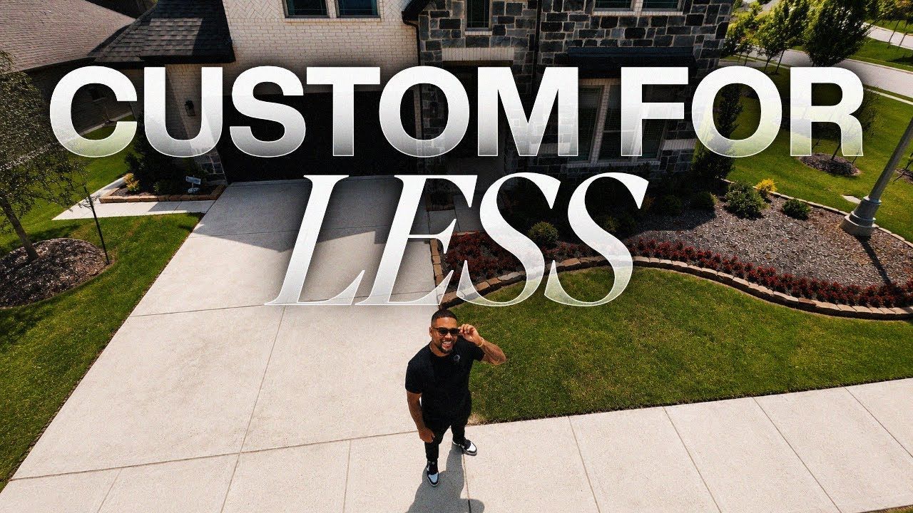 Custom concrete driveway with landscaped yard and a person standing on the sidewalk under “CUSTOM FOR LESS” text