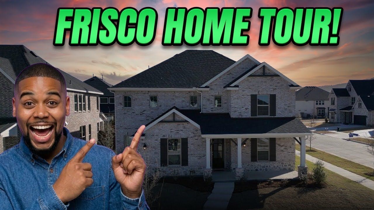 A man smiling and pointing toward a two-story brick house in a suburban neighborhood under a sunset sky.