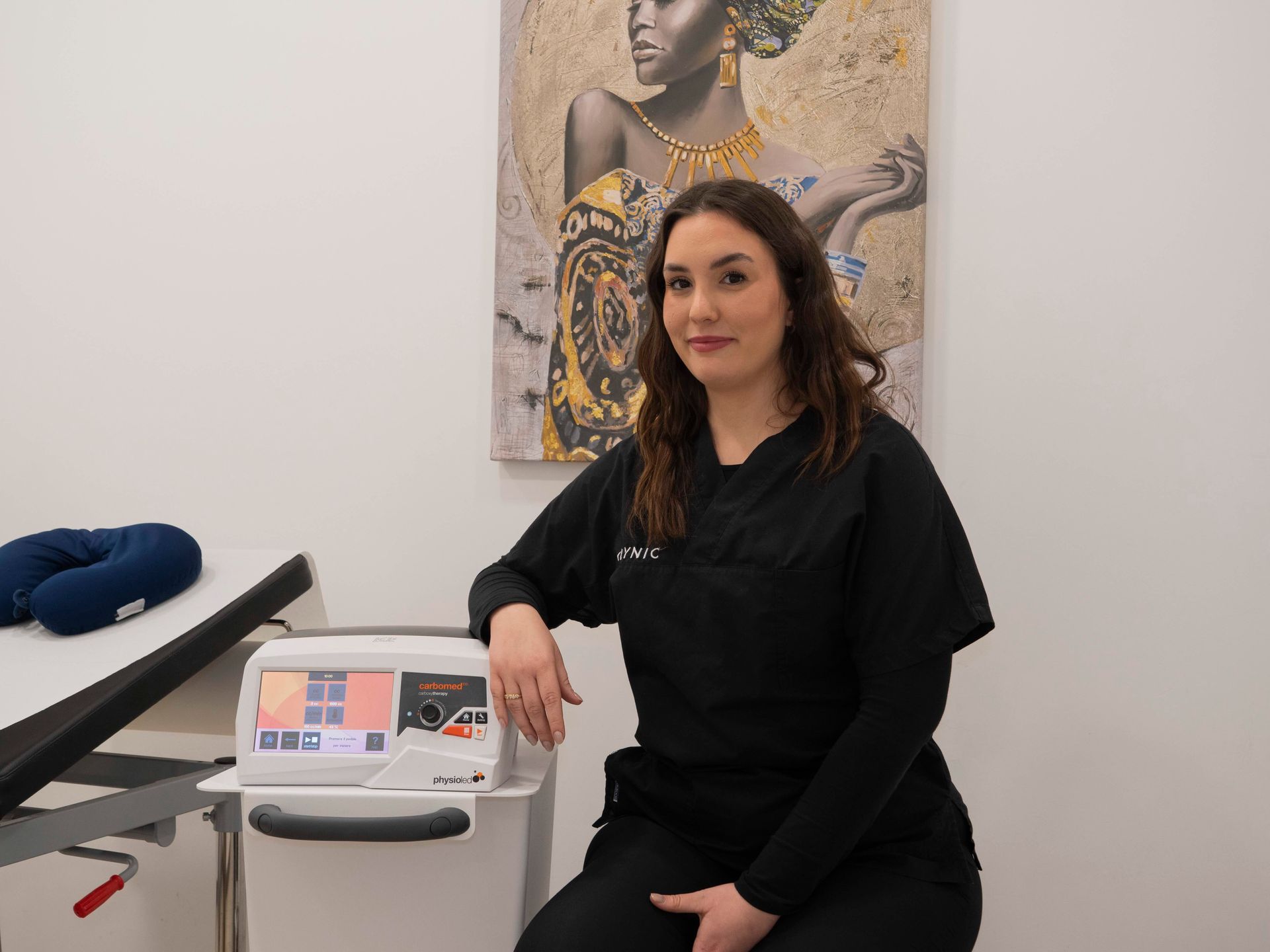 Una donna è seduta su uno sgabello davanti a una macchina in una stanza.