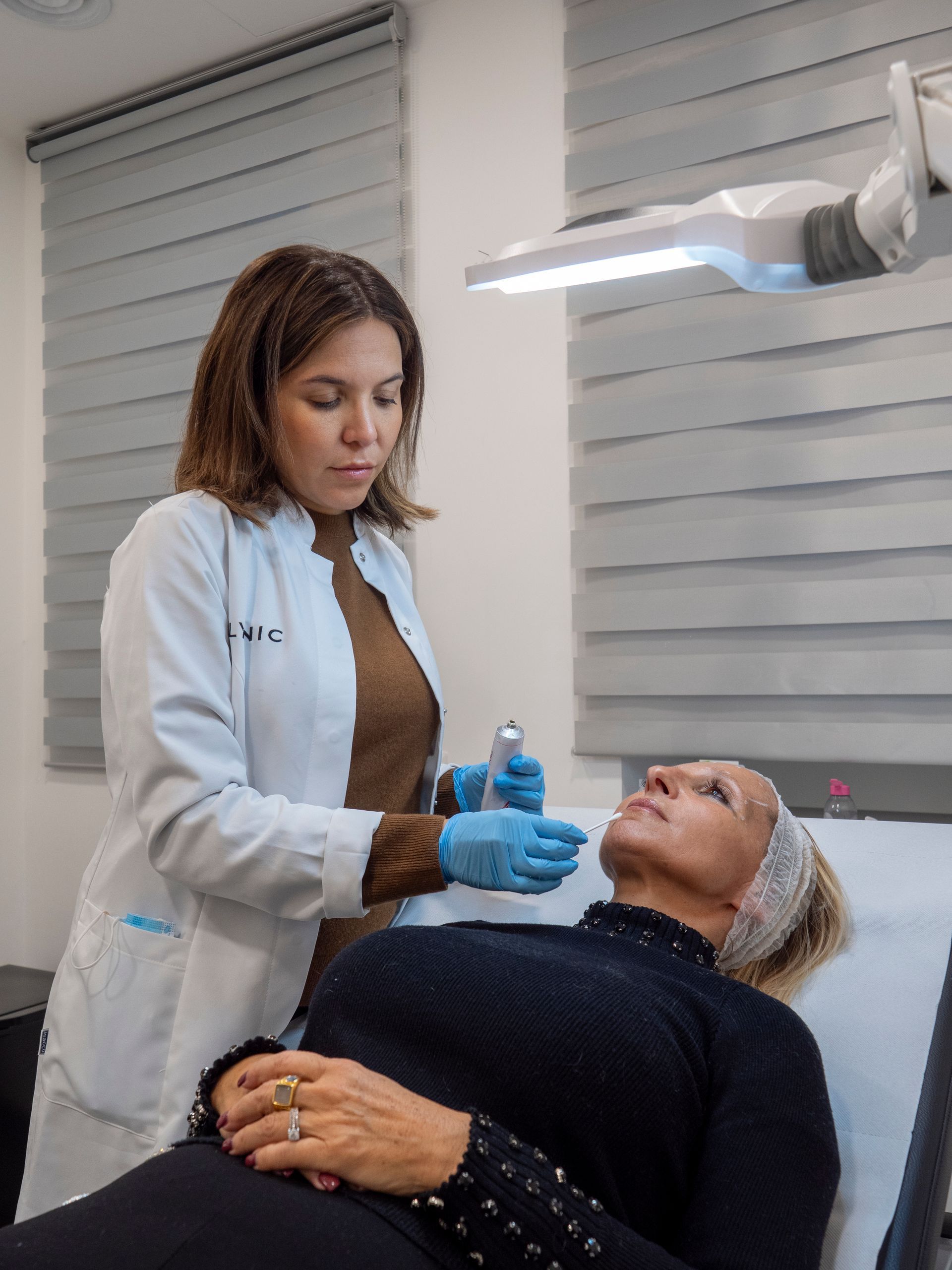 Una donna è sdraiata su un letto mentre un medico le esamina il viso.