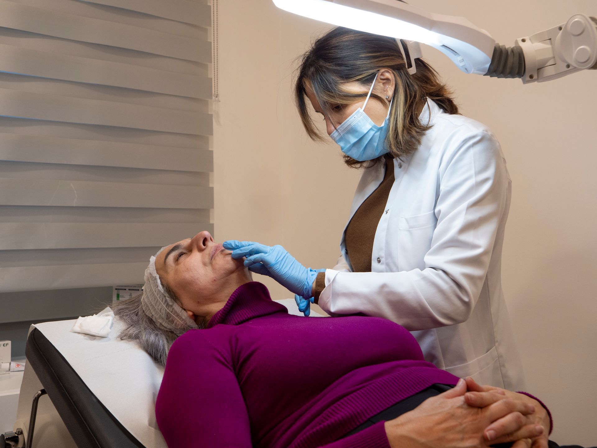 Una donna è sdraiata su un tavolo mentre un medico le esamina il viso.