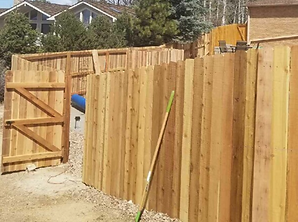 A wooden fence with a gate and a shovel in front of it.