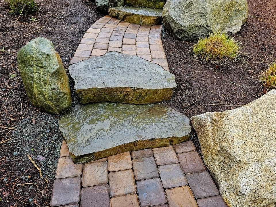 A stone walkway surrounded by rocks and bricks in a garden.