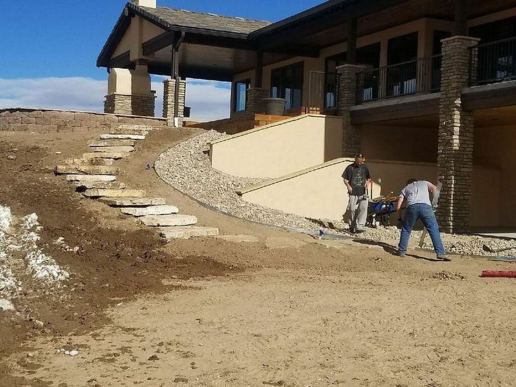 A man is standing in the dirt in front of a house