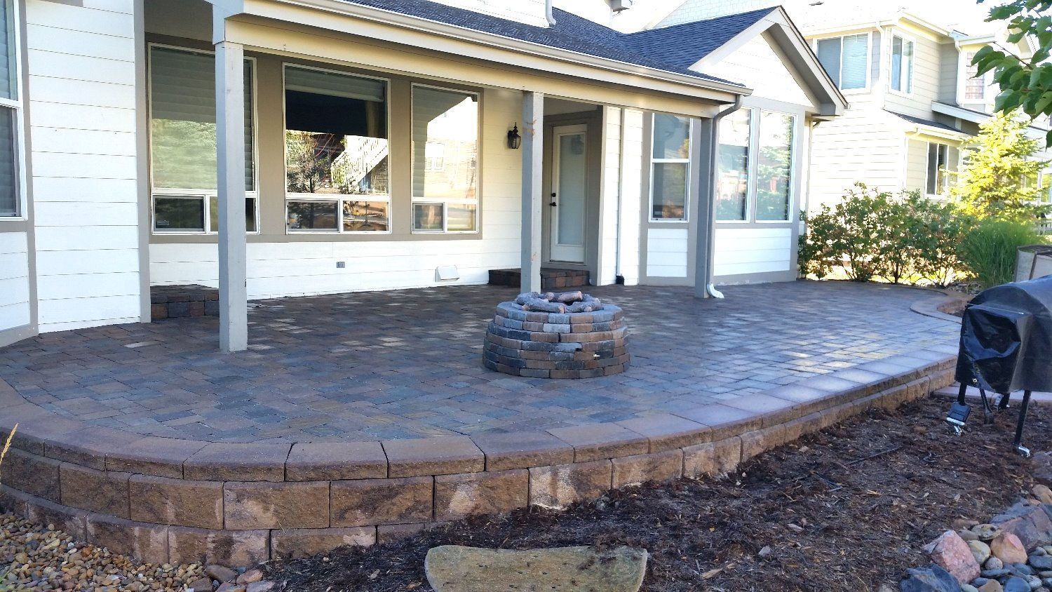 A house with a patio and a fire pit in front of it.