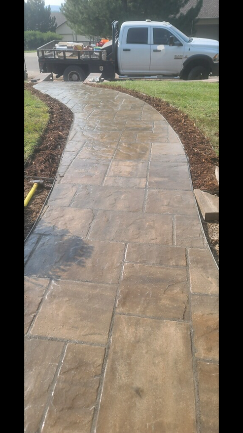 A white truck is parked on the side of a concrete walkway.