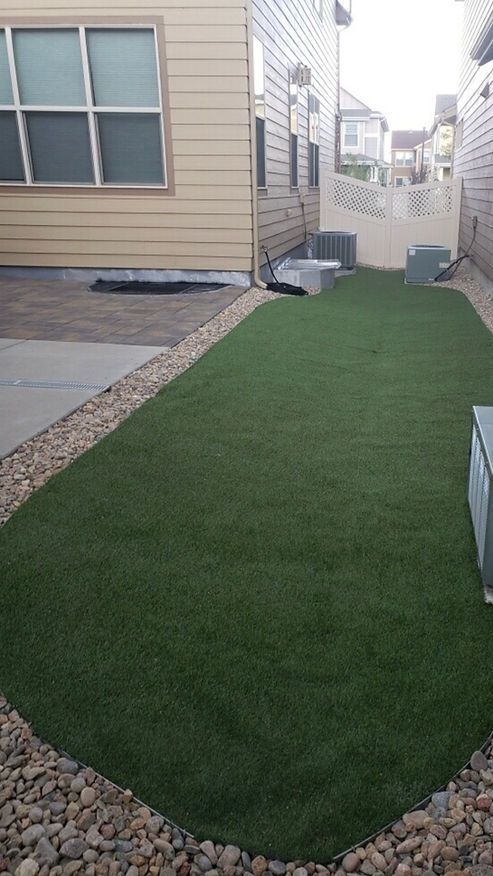 A backyard with a lush green lawn and a house in the background.