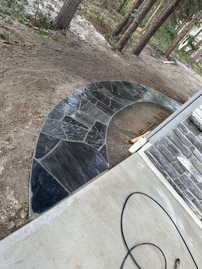 A stone walkway is being built on the side of a house.