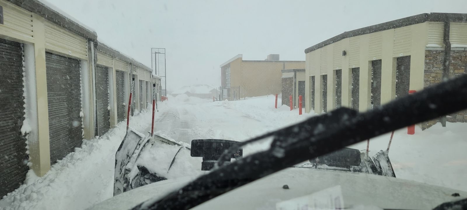 A snow plow is clearing snow from a parking lot