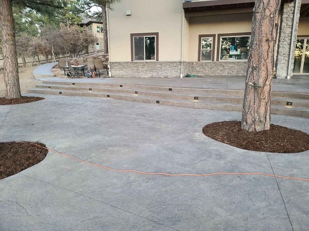 Exterior of a building with a paved courtyard, trees, and mulch beds.