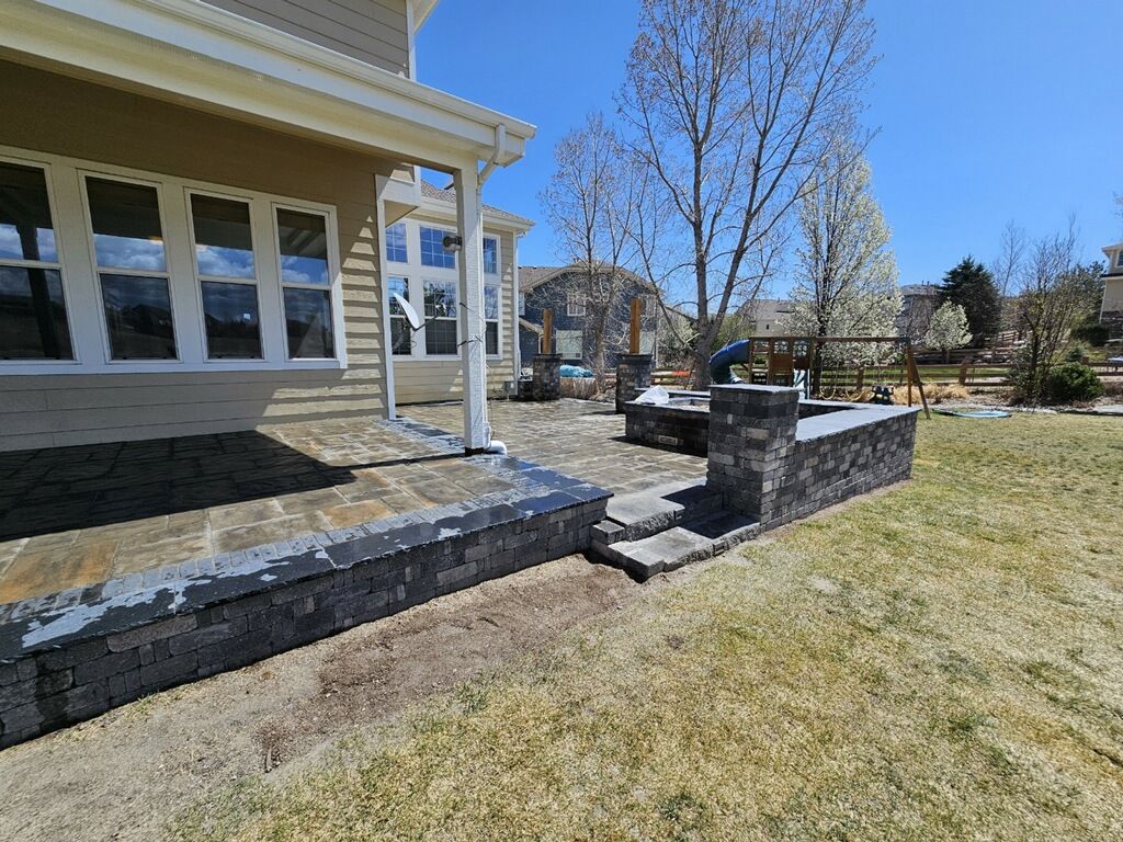 A house with a patio and a brick wall in front of it.