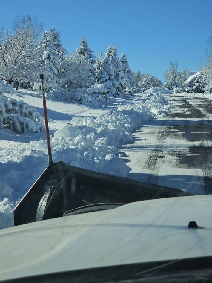 A snow plow is clearing a snow covered road