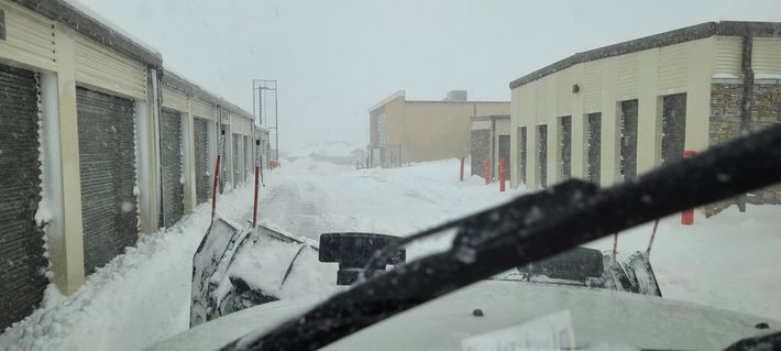 A snow plow is clearing snow from a parking lot.