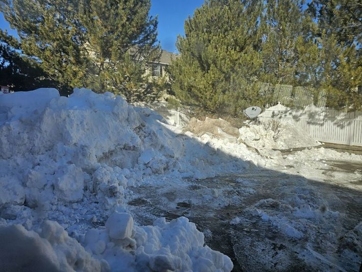 A pile of snow is sitting on the side of a road.