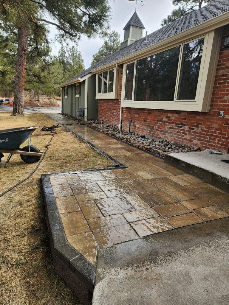 A wheelbarrow is parked in front of a brick house.