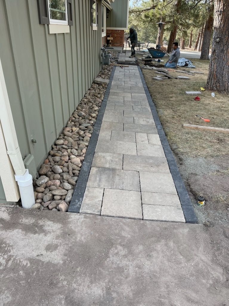 A stone walkway is being built in front of a house.