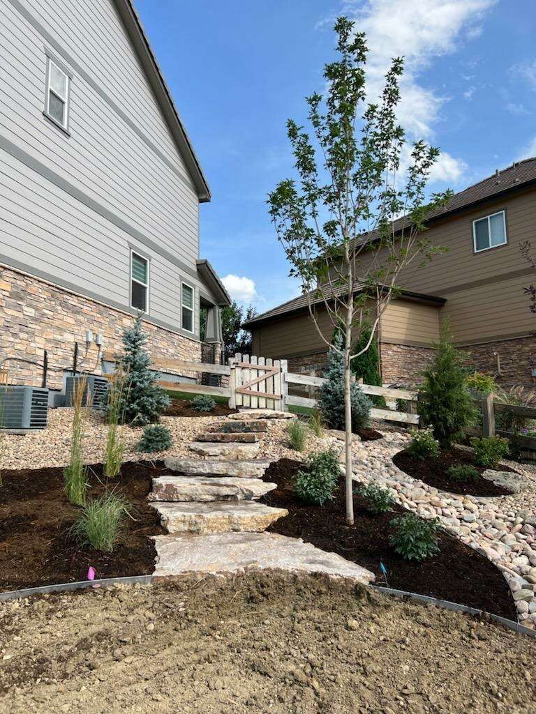 A house with stairs leading up to it and a tree in front of it.