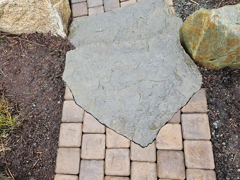A brick walkway with a large rock in the middle