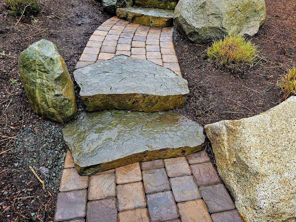 A stone walkway surrounded by rocks and bricks in a garden