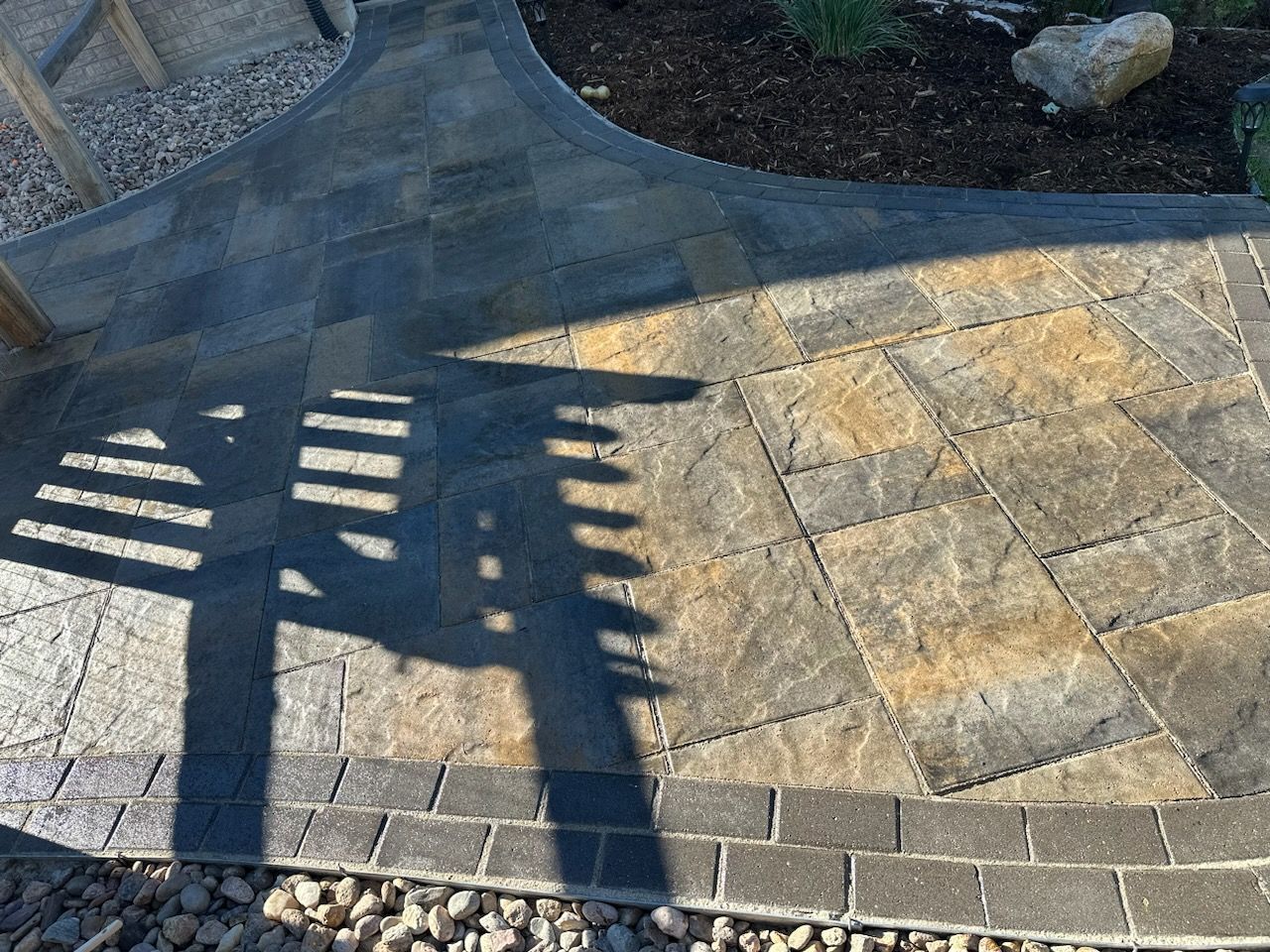 A shadow of a person is cast on a brick walkway.