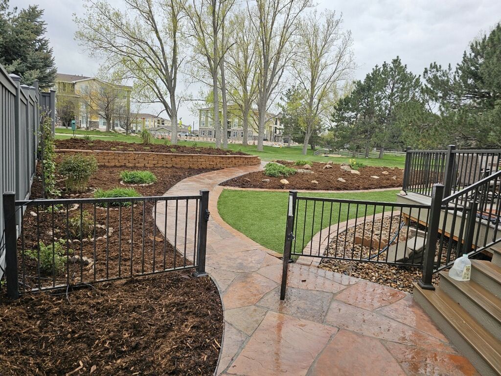 A walkway leading to a fenced in yard with trees in the background