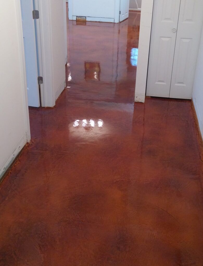 A hallway with a stained concrete floor and a white door.