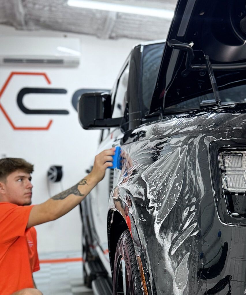 A man is cleaning a black truck with a sponge
